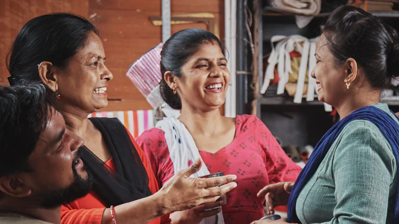 Colleagues at a tailoring unit laughing together during a tea break