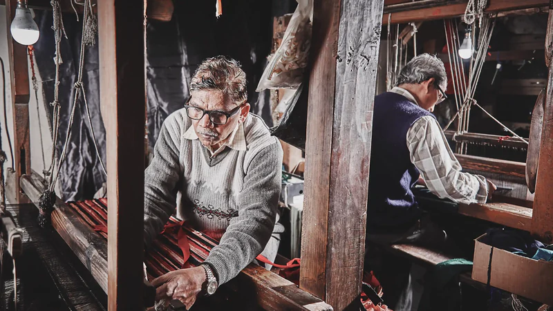 Moolchand and Kishanpal weaving at wooden hand looms in a workshop